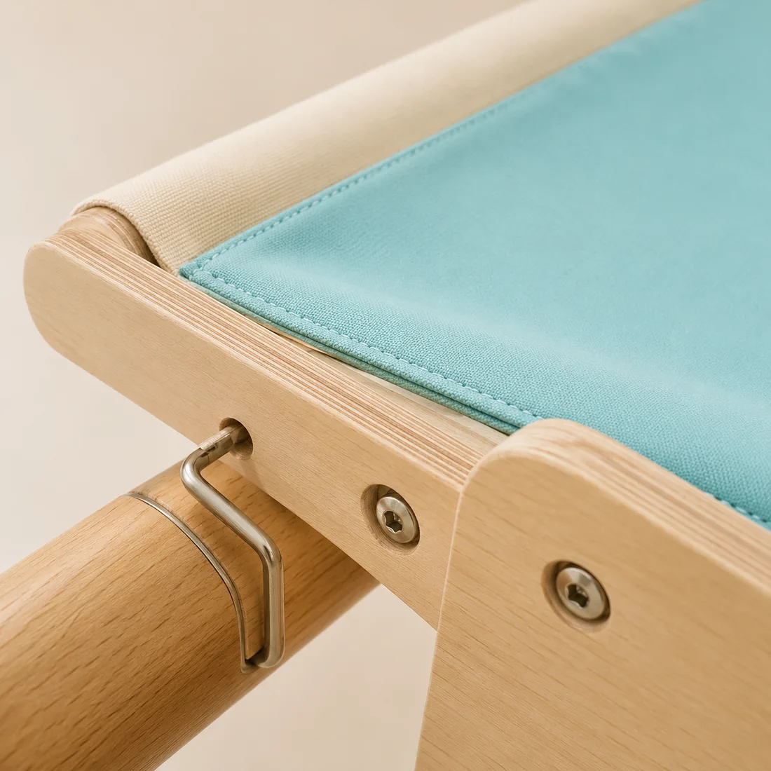 Macro shot of the corner of the teal perch: grain of the varnished plywood, metal screw and canvas stitching