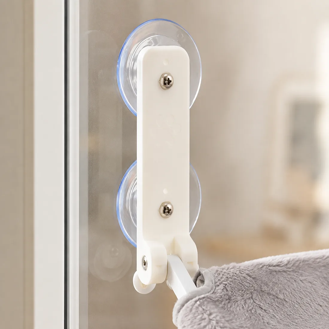 Macro shot of a white arm and its two clear suction cups pressed on the glass, metal screws in sharp focus