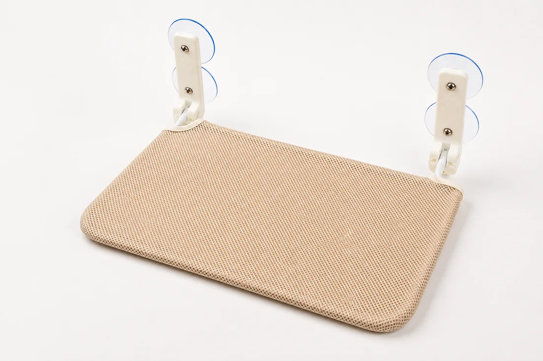 Studio shot of the beige platform unfolded: four suction cups, two white arms, screws and rounded corners